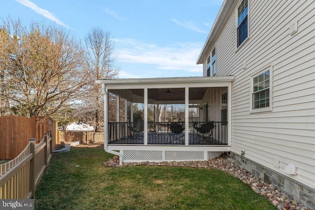 exterior space with a fenced backyard, ceiling fan, a sunroom, and a yard