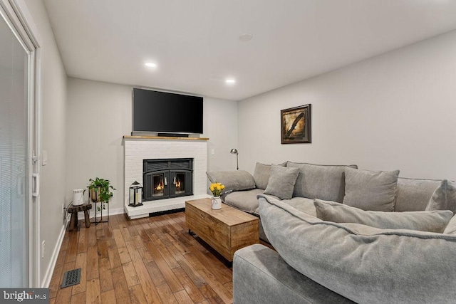 living area featuring recessed lighting, wood finished floors, visible vents, baseboards, and a fireplace