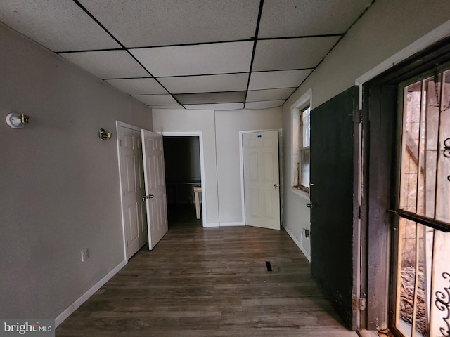 hallway featuring dark wood-type flooring and a paneled ceiling