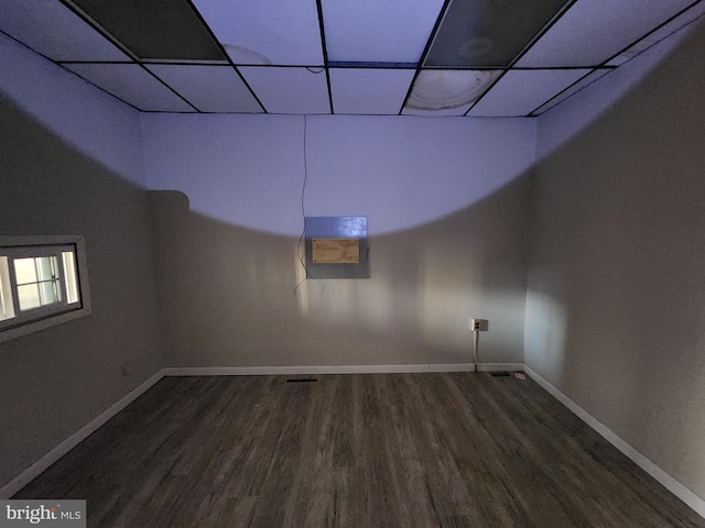 basement featuring dark wood-type flooring and a paneled ceiling