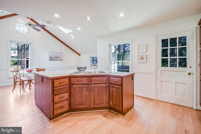 kitchen featuring lofted ceiling with skylight, a kitchen island, and a wealth of natural light