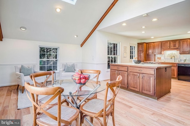 dining space with sink, light hardwood / wood-style floors, and vaulted ceiling