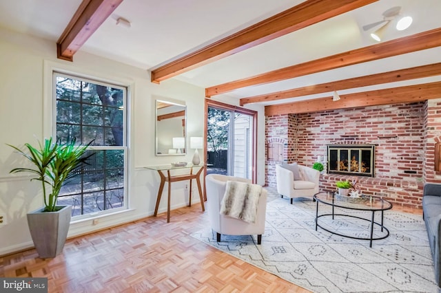 living room with a brick fireplace, beamed ceiling, light parquet flooring, and brick wall