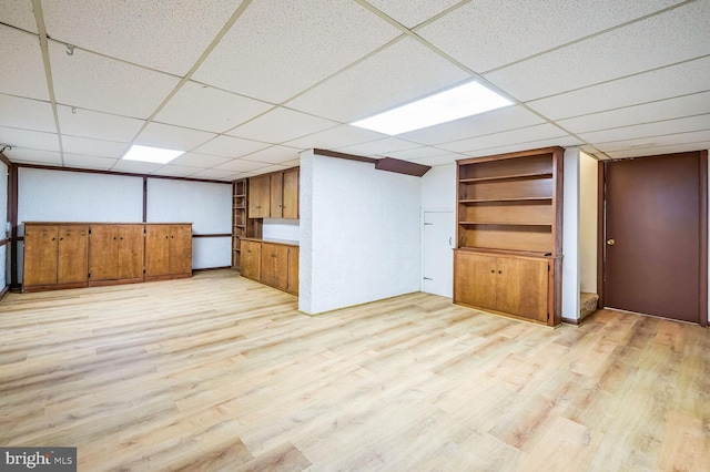 interior space featuring a paneled ceiling and light hardwood / wood-style floors