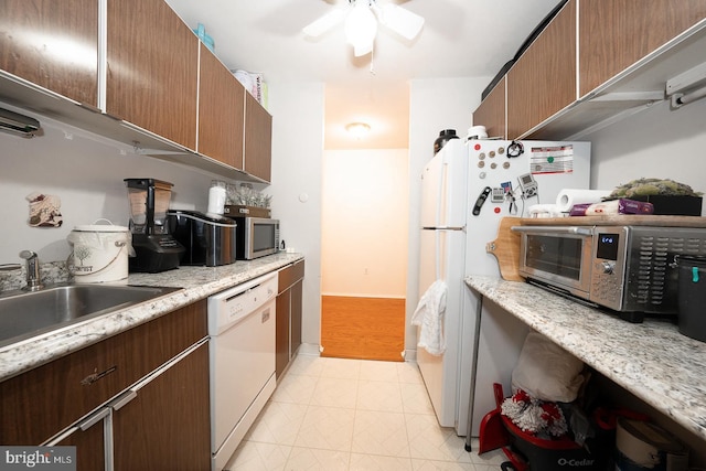 kitchen featuring ceiling fan, sink, light stone counters, and white appliances