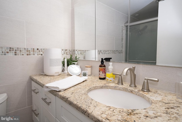 bathroom with tasteful backsplash, vanity, tile walls, and toilet