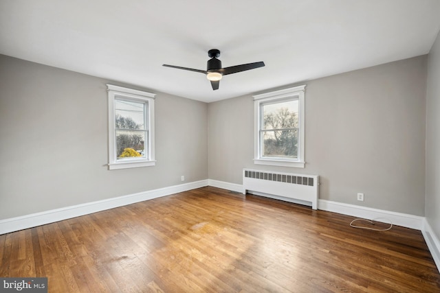 unfurnished room featuring radiator heating unit, wood-type flooring, and plenty of natural light