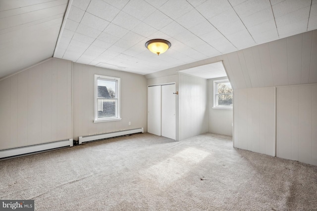 additional living space with lofted ceiling, a baseboard heating unit, and carpet