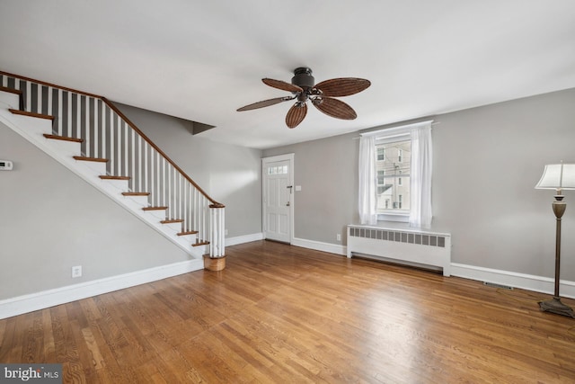 entrance foyer with ceiling fan, radiator heating unit, and wood-type flooring