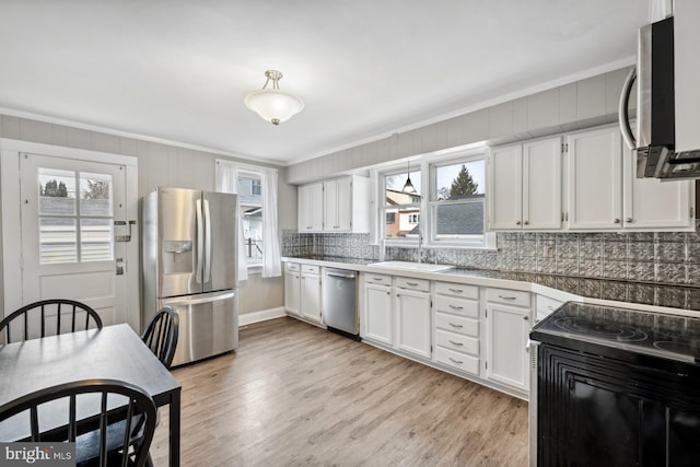 kitchen with sink, white cabinetry, tasteful backsplash, light wood-type flooring, and stainless steel appliances