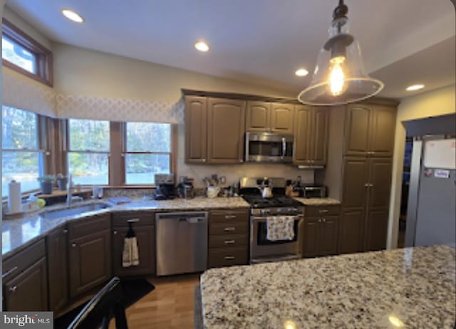 kitchen featuring sink, light wood-type flooring, light stone countertops, and appliances with stainless steel finishes