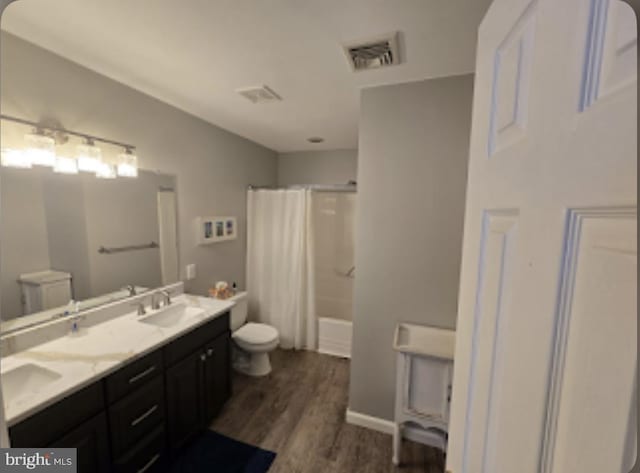 full bathroom with vanity, hardwood / wood-style flooring, shower / bath combo, and toilet