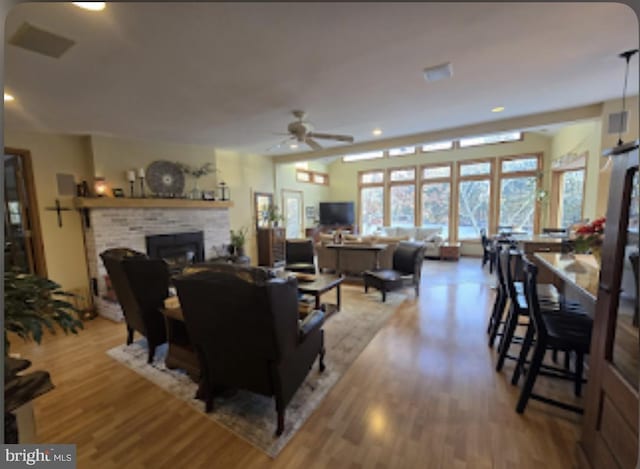 living room featuring ceiling fan, a fireplace, and light hardwood / wood-style flooring