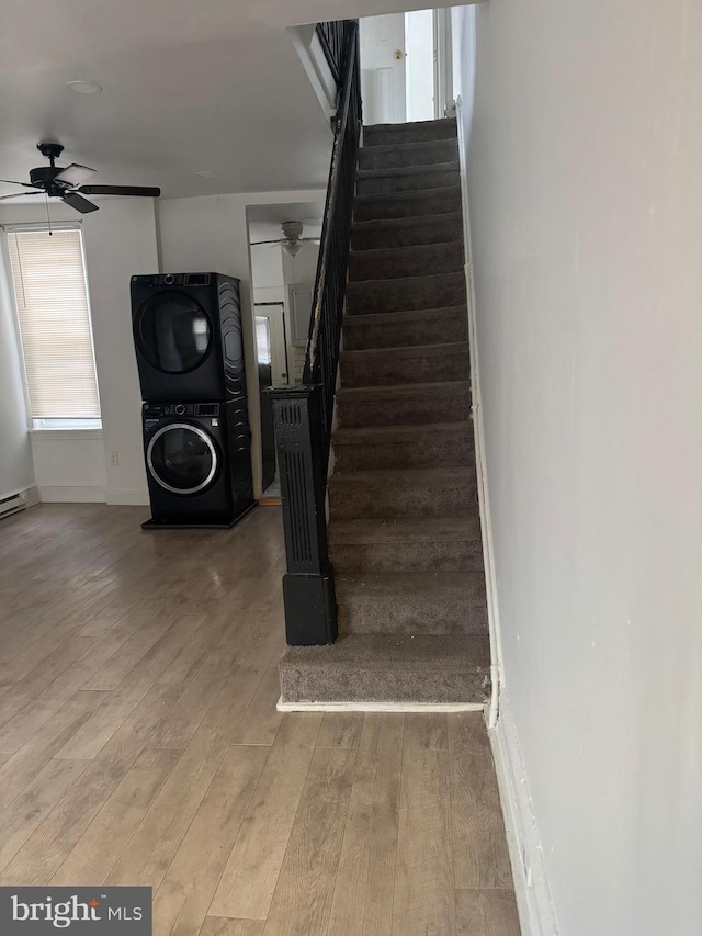 stairs featuring ceiling fan, baseboards, wood finished floors, and stacked washer and clothes dryer