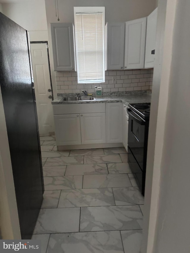 kitchen with decorative backsplash, black electric range oven, marble finish floor, white cabinetry, and a sink