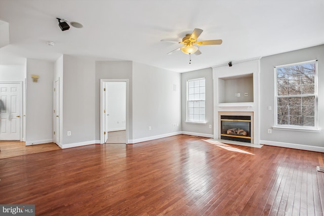 unfurnished living room with a fireplace with flush hearth, a healthy amount of sunlight, and hardwood / wood-style floors