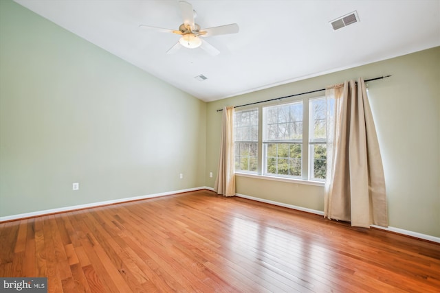 empty room with ceiling fan, lofted ceiling, visible vents, baseboards, and light wood-style floors