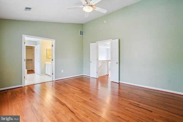 unfurnished bedroom featuring lofted ceiling, light wood-type flooring, a spacious closet, and visible vents