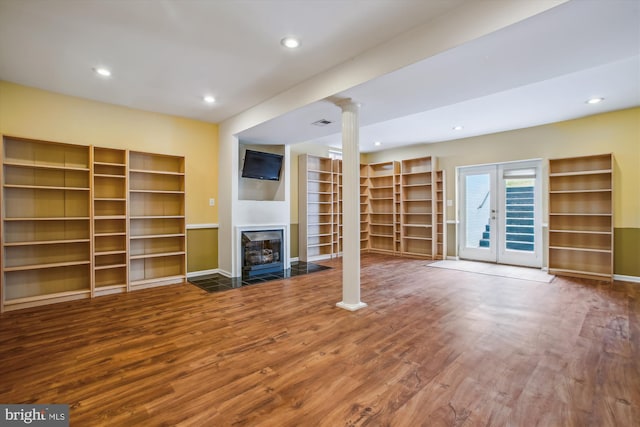 unfurnished living room featuring a fireplace, recessed lighting, baseboards, wood finished floors, and ornate columns