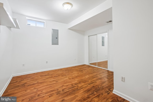 basement with electric panel, baseboards, and wood finished floors