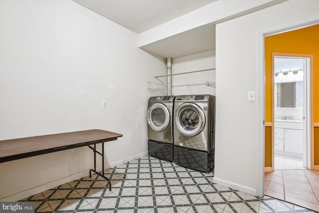 laundry area featuring laundry area, a sink, baseboards, tile patterned floors, and washing machine and clothes dryer