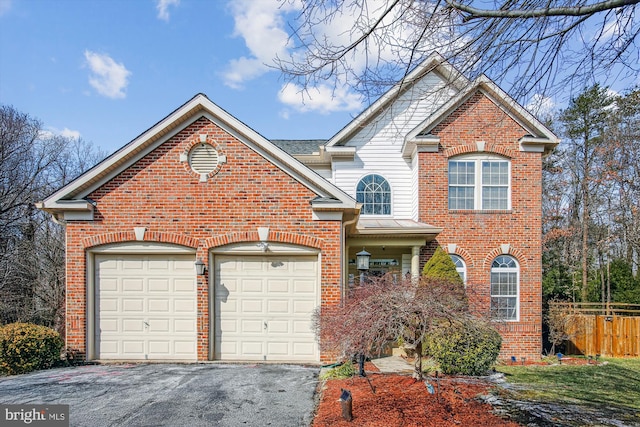 view of front of house with brick siding, fence, driveway, and an attached garage