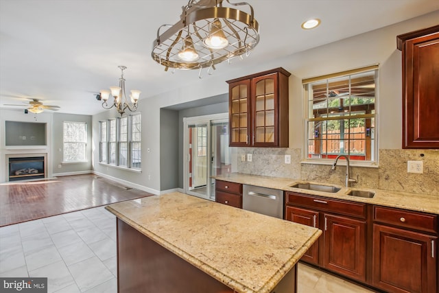 kitchen with dishwasher, backsplash, a sink, and a glass covered fireplace