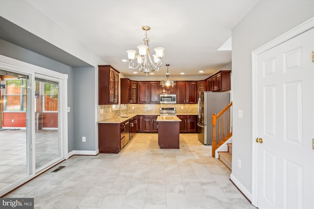 kitchen with appliances with stainless steel finishes, backsplash, a center island, light countertops, and a sink