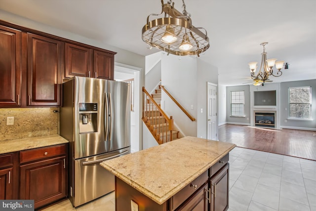 kitchen featuring light stone counters, pendant lighting, stainless steel refrigerator with ice dispenser, and backsplash