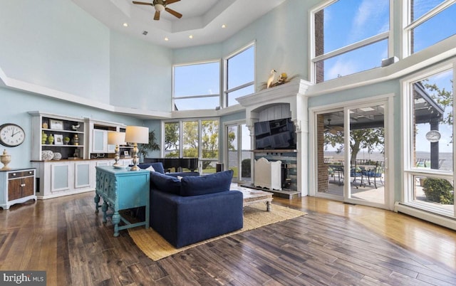 living room featuring a baseboard radiator, a towering ceiling, hardwood / wood-style floors, and ceiling fan