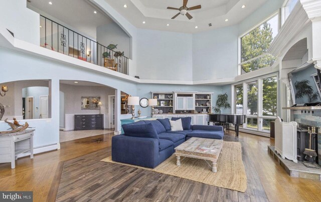 living room featuring ceiling fan, a tray ceiling, and hardwood / wood-style floors