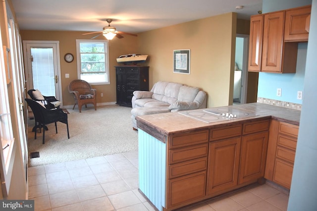 kitchen with tile counters, light colored carpet, kitchen peninsula, and ceiling fan