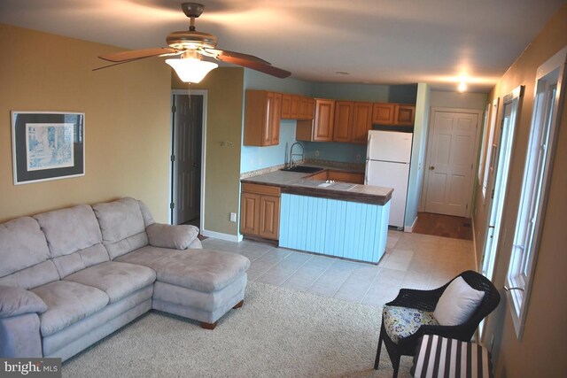 kitchen featuring sink, light carpet, kitchen peninsula, white fridge, and ceiling fan