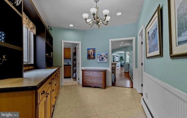 hall featuring a baseboard heating unit, light tile patterned floors, and a notable chandelier