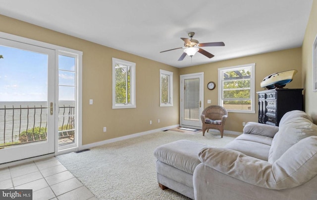 living room featuring light tile patterned floors, ceiling fan, and a water view