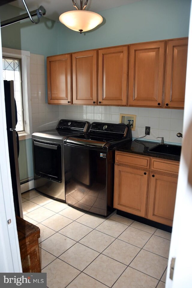 washroom featuring sink, light tile patterned floors, baseboard heating, cabinets, and separate washer and dryer