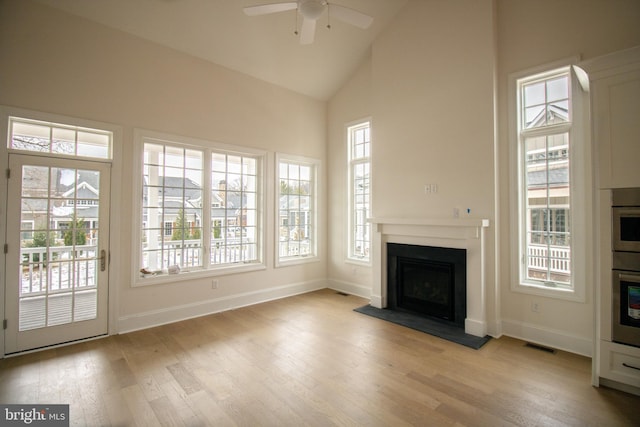 unfurnished living room with ceiling fan, high vaulted ceiling, and light wood-type flooring