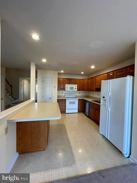 kitchen with sink, white appliances, and kitchen peninsula