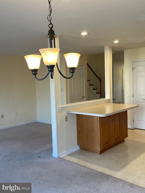 kitchen featuring decorative light fixtures, a chandelier, and light carpet