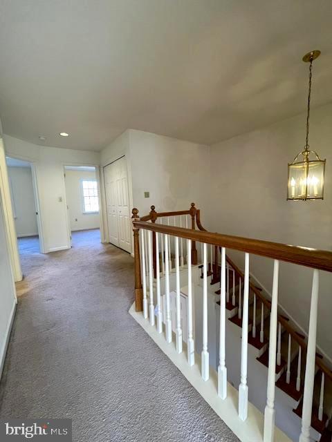 hall featuring carpet flooring and a notable chandelier