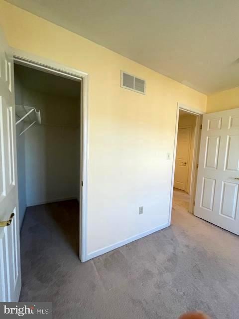 unfurnished bedroom with a spacious closet, a closet, and carpet flooring