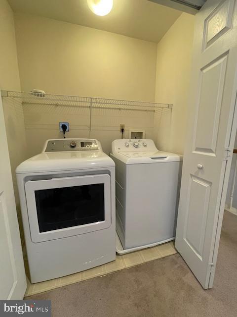 washroom with washing machine and clothes dryer and light carpet