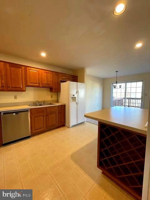 kitchen with stainless steel dishwasher, sink, white fridge with ice dispenser, and pendant lighting