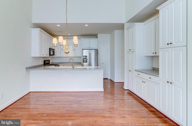 kitchen featuring white cabinetry, stainless steel refrigerator with ice dispenser, range, and decorative light fixtures