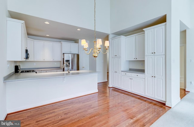 kitchen with stainless steel fridge, white cabinets, an inviting chandelier, and decorative light fixtures