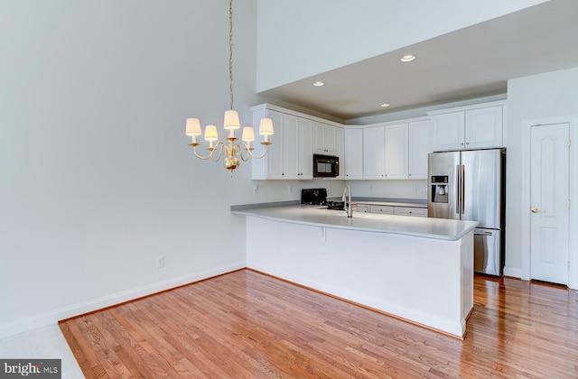 kitchen featuring range, hanging light fixtures, stainless steel refrigerator with ice dispenser, white cabinets, and kitchen peninsula