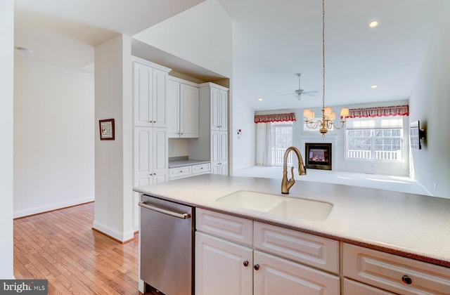 kitchen with sink, decorative light fixtures, light hardwood / wood-style flooring, stainless steel dishwasher, and white cabinets