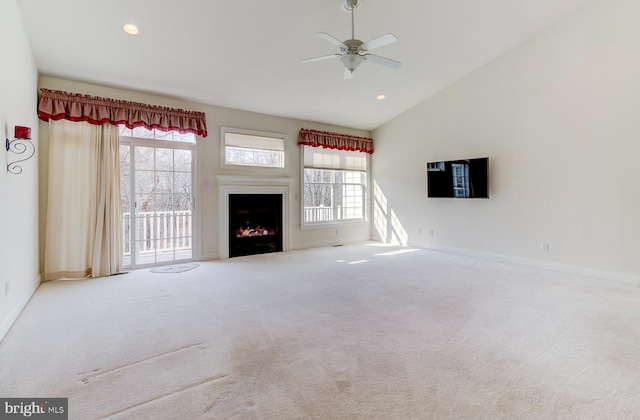 unfurnished living room with vaulted ceiling, plenty of natural light, carpet floors, and ceiling fan