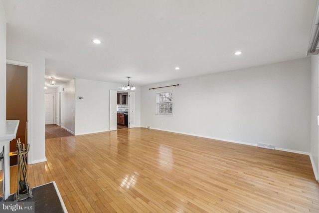 unfurnished living room featuring an inviting chandelier and light wood-type flooring