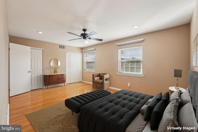 bedroom with two closets, ceiling fan, and light wood-type flooring